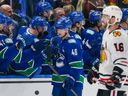 Jason Dickinson  of the Chicago Blackhawks skates on as Elias Pettersson  of the Vancouver Canucks is congratulated at the player's bench after scoring a goal during the NHL game at Rogers Arena on November 16, 2024 in Vancouver.