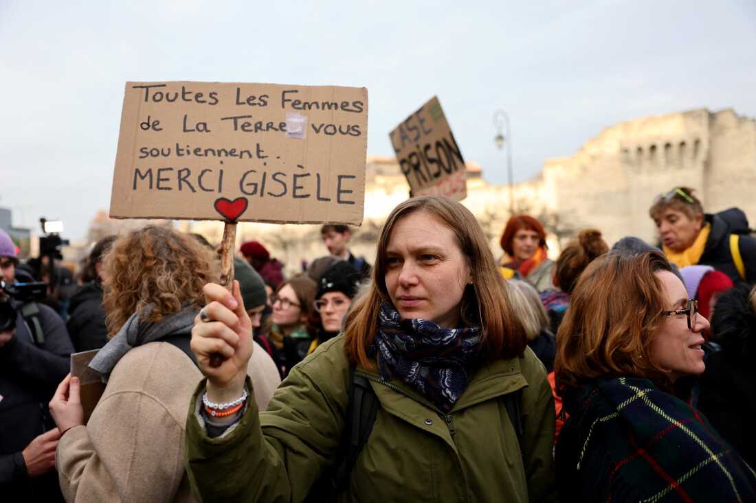 A woman holds a placard reading in French 