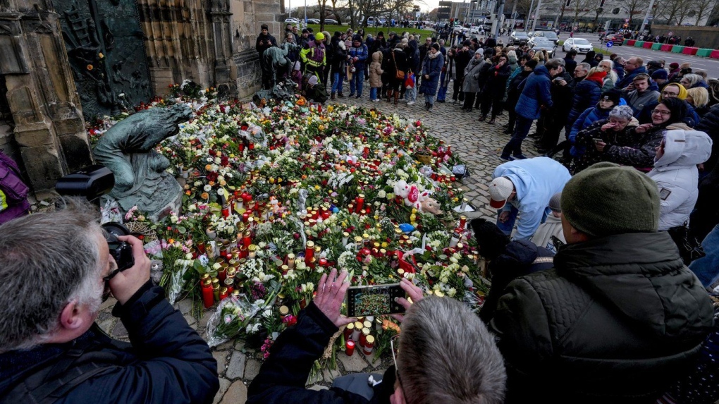 People lay flowers at the entrance of a church near a Christmas Market, where a car drove into a crowd on Friday evening, in Magdeburg, Germany, Saturday, Dec. 21, 2024. (AP Photo/Michael Probst)