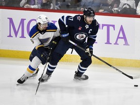 Winnipeg Jets' Adam Lowry looks to pass the puck as he is checked by St. Louis Blues' Jordan Kyrou Tuesday night. Fred Greenslade/The Canadian Press