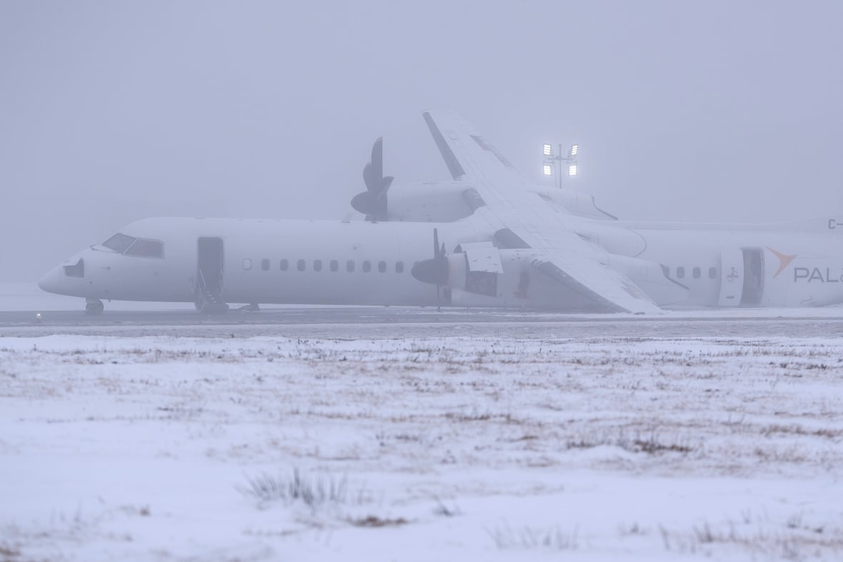 A white plane is shown tilting to its left side on an airport runway.