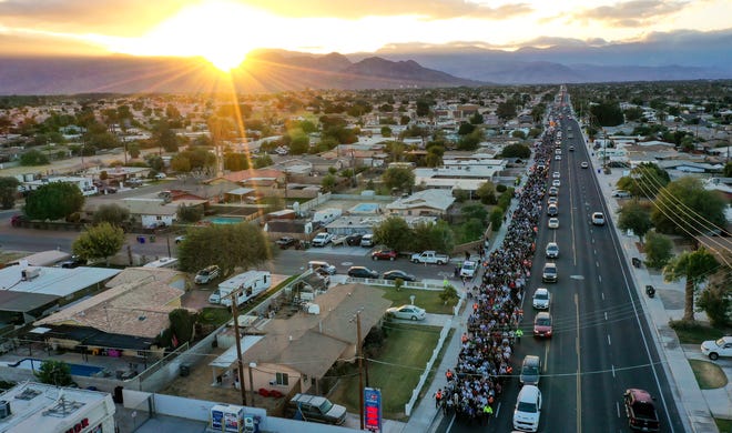 The sun begins to set as hundreds of people walk along Miles Ave during the Virgen de Guadalupe pilgrimage through the Coachella Valley as it passes through Indio, Calif., Dec. 12, 2024.