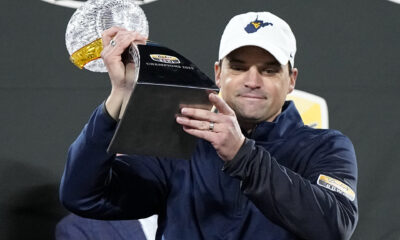 A man is wearing a ball cap featuring the shape of West Virginia.