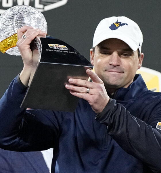 A man is wearing a ball cap featuring the shape of West Virginia.