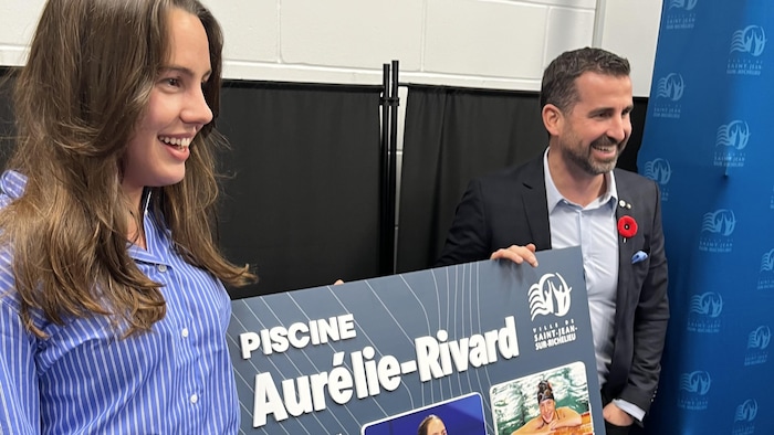 Les deux tiennent l'enseigne présentant le nouveau nom de la piscine. 