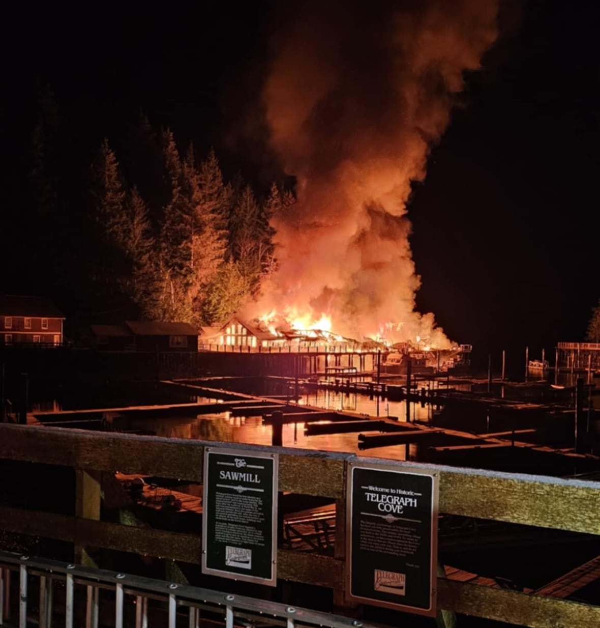 A wooden restaurant on the shoreline is engulfed in flames.