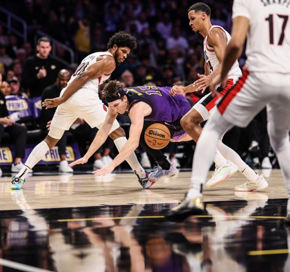 Lakers guard Austin Reaves, center, loses control of the ball