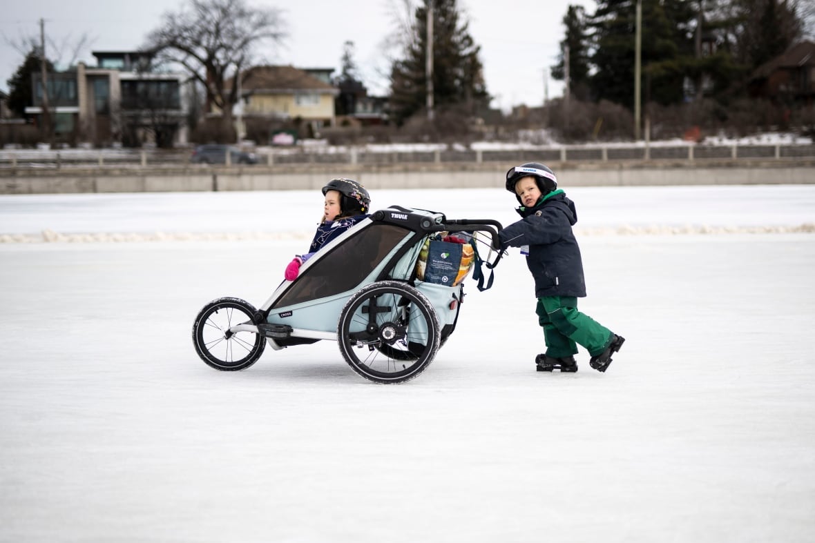 A small child pushes a baby in a stroller on the Rideau Canal skateway.