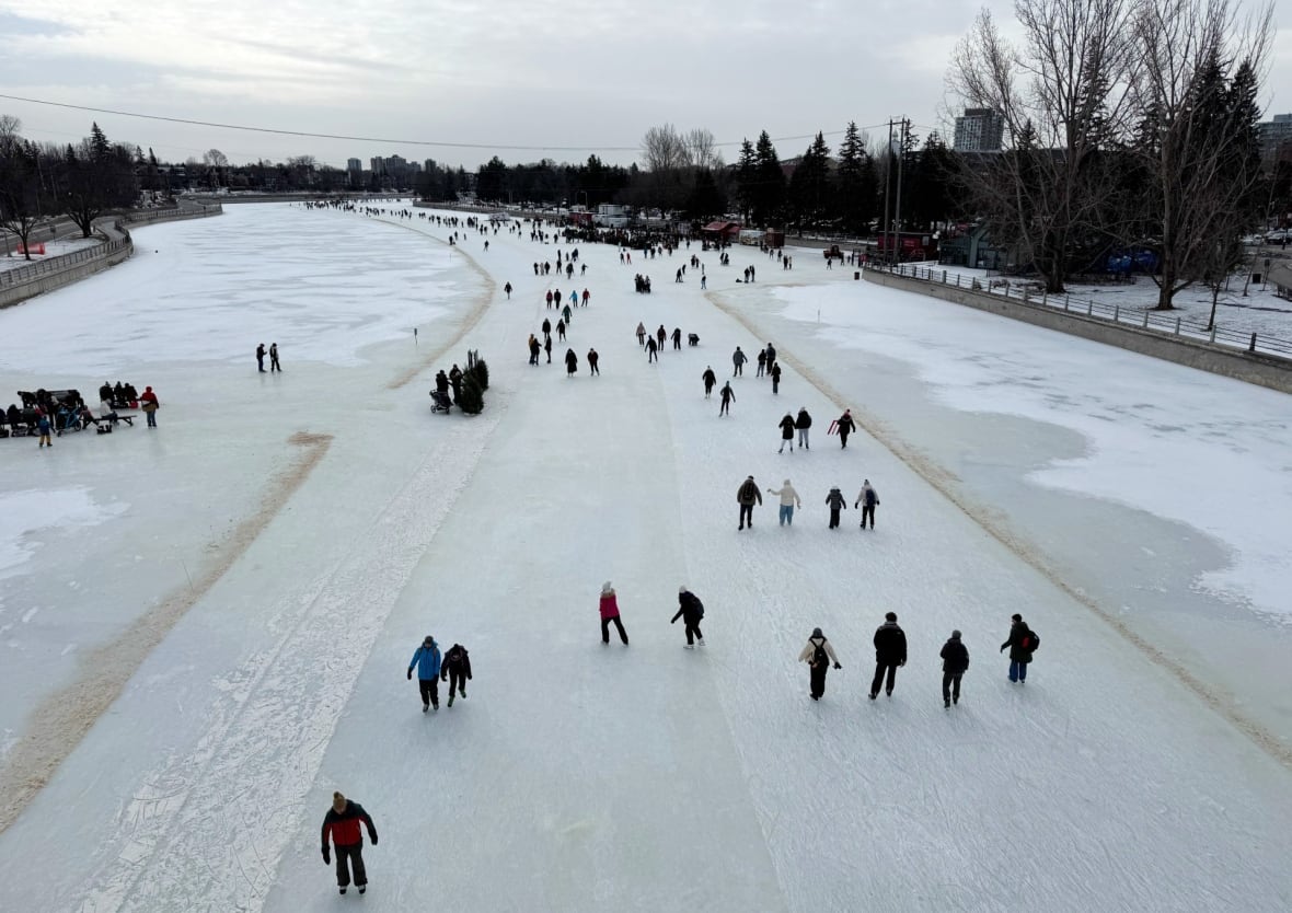 Dozens of people are seen from above skating on a frozen canal.