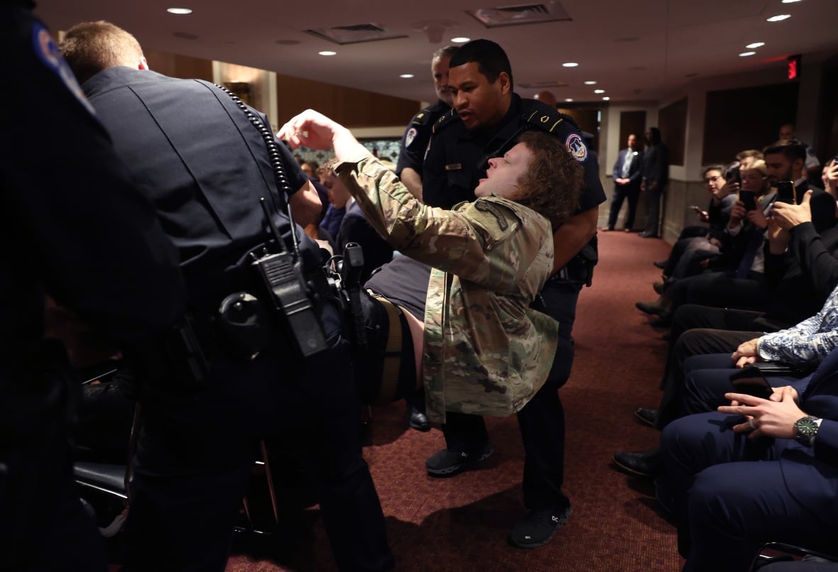 A person is shown horizontal, being grabbed by security officers in an indoor setting.