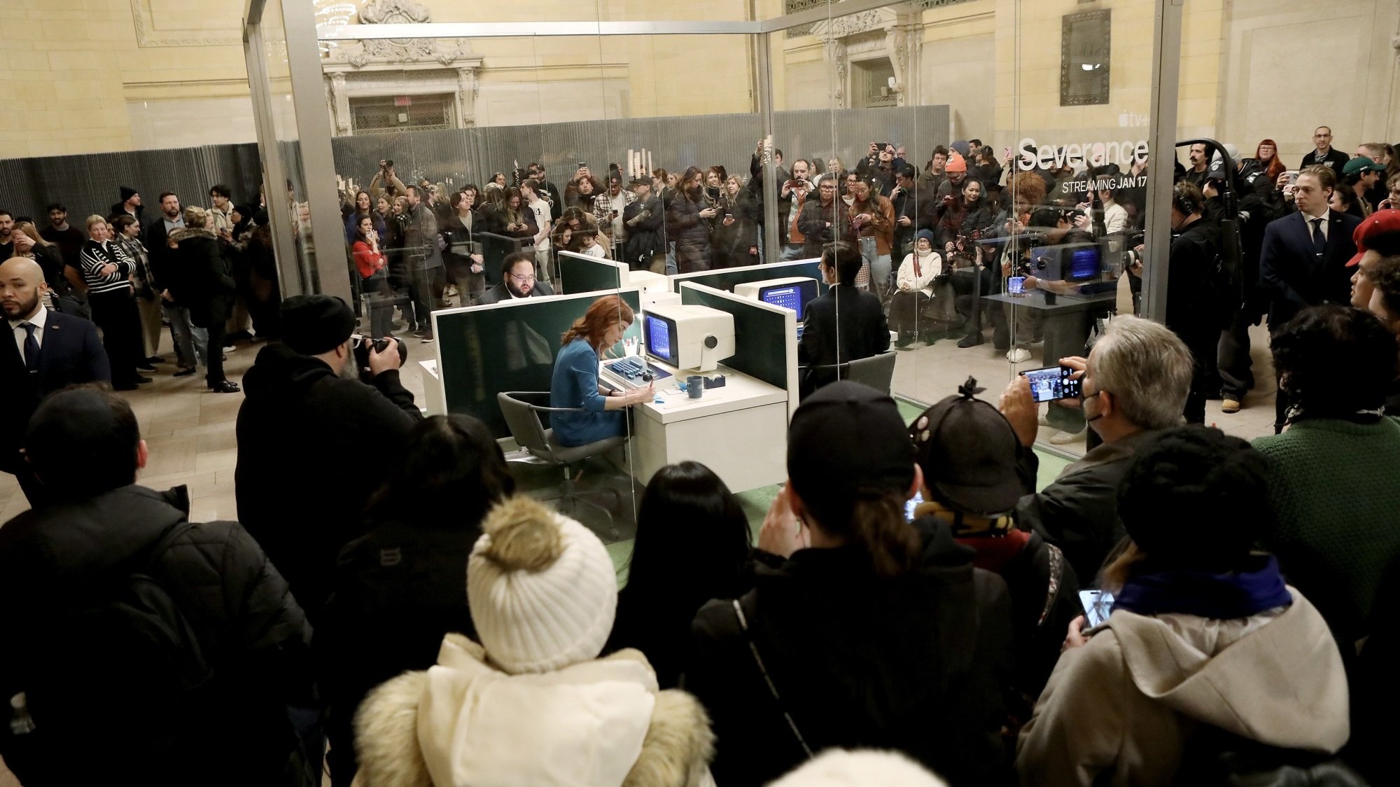 A crowd gathers around a glass cube with the 